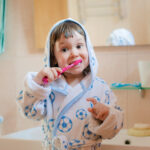A little girl or child brushes teeth in the bathroom. Hygiene of the oral cavity. Children's toothpaste. the kid is looking at the toothbrush with the paste Healthy Habits